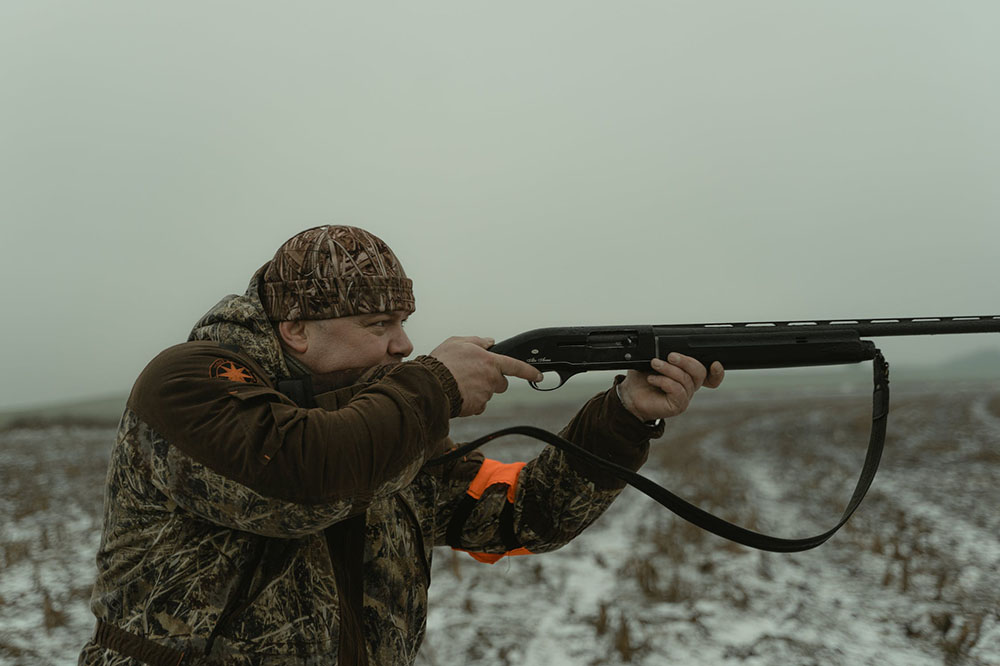 a hunter is aiming at target with a scope