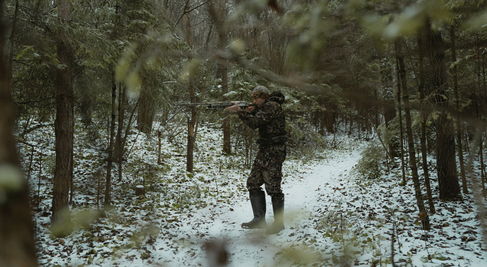 A hunter in hunting boots is stalking in the forest