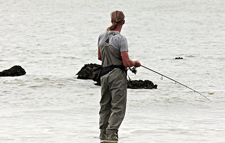 A fisherman in deck boots is fishing