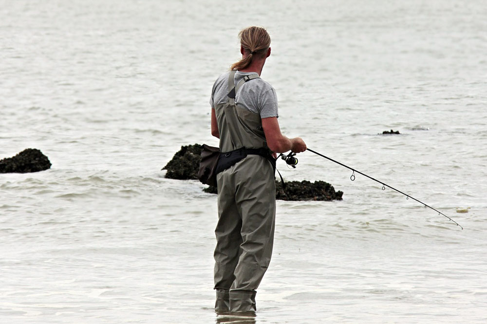 A fisherman in deck boots is by the river