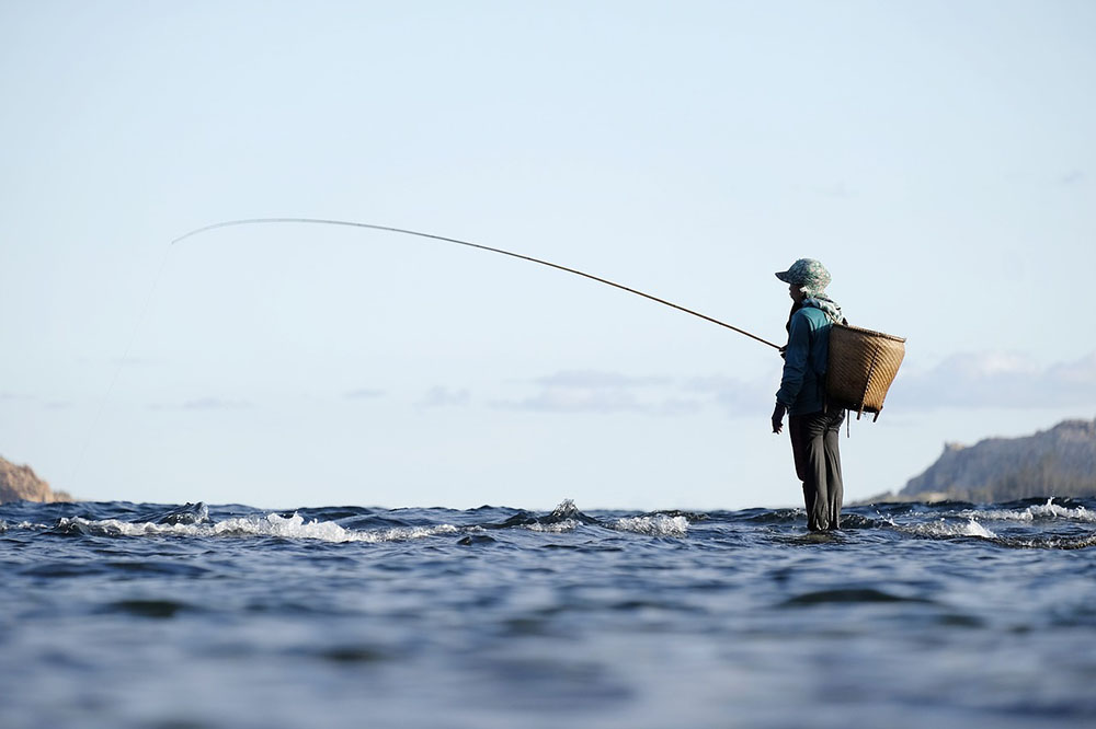 A fishman is fishing by the river