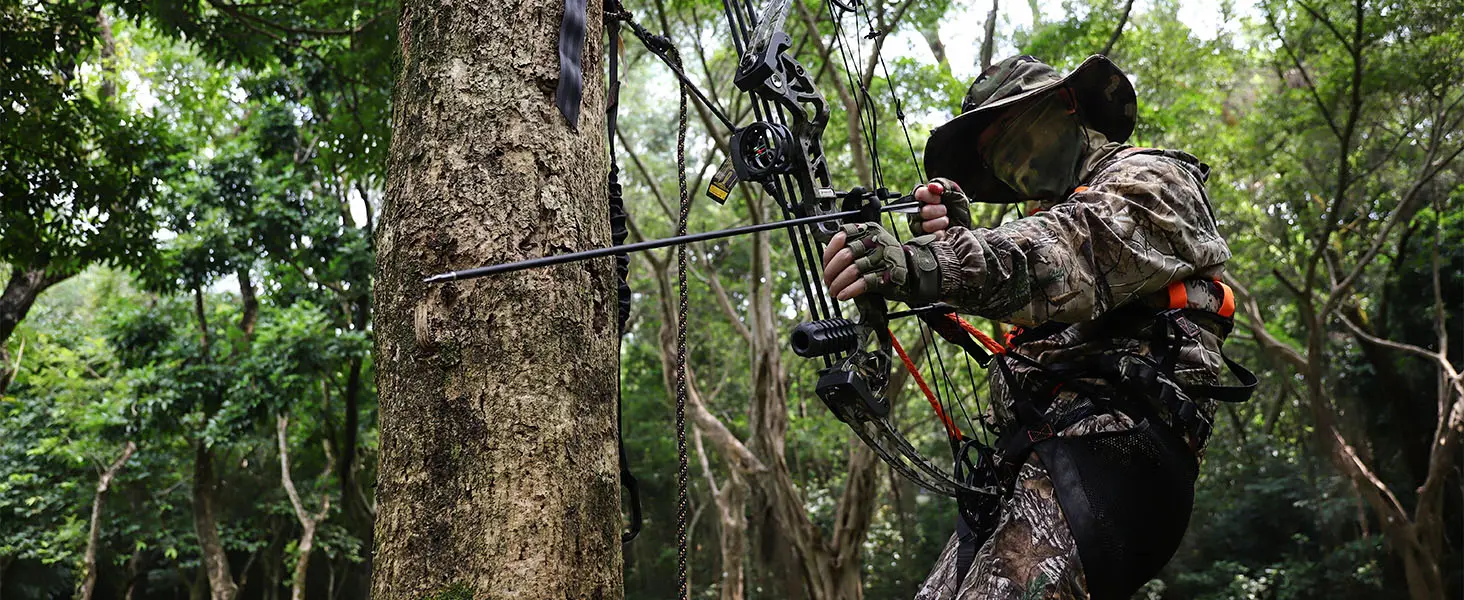 Bowhunter wearing a saddle hunting harness while drawing a bow in a tree