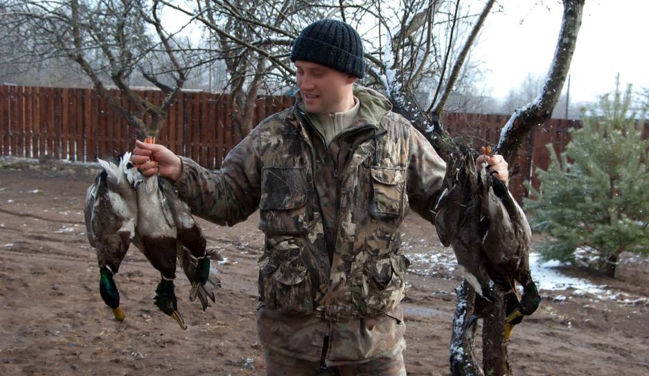 a hunter harvested a lot of ducks successfully and held the ducks with his hands