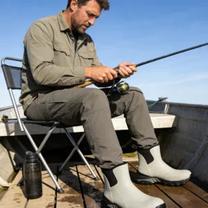 A man wearing grey ankle deck boots while fishing on a boat, highlighting the non-slip grip on wet wooden decks