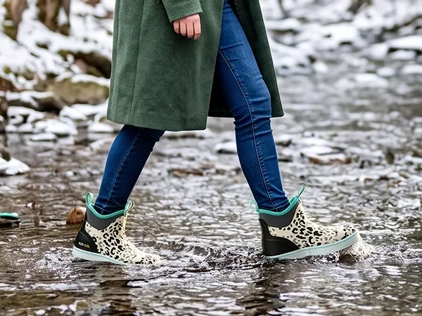 Woman wearing waterproof boots while crossing a stream