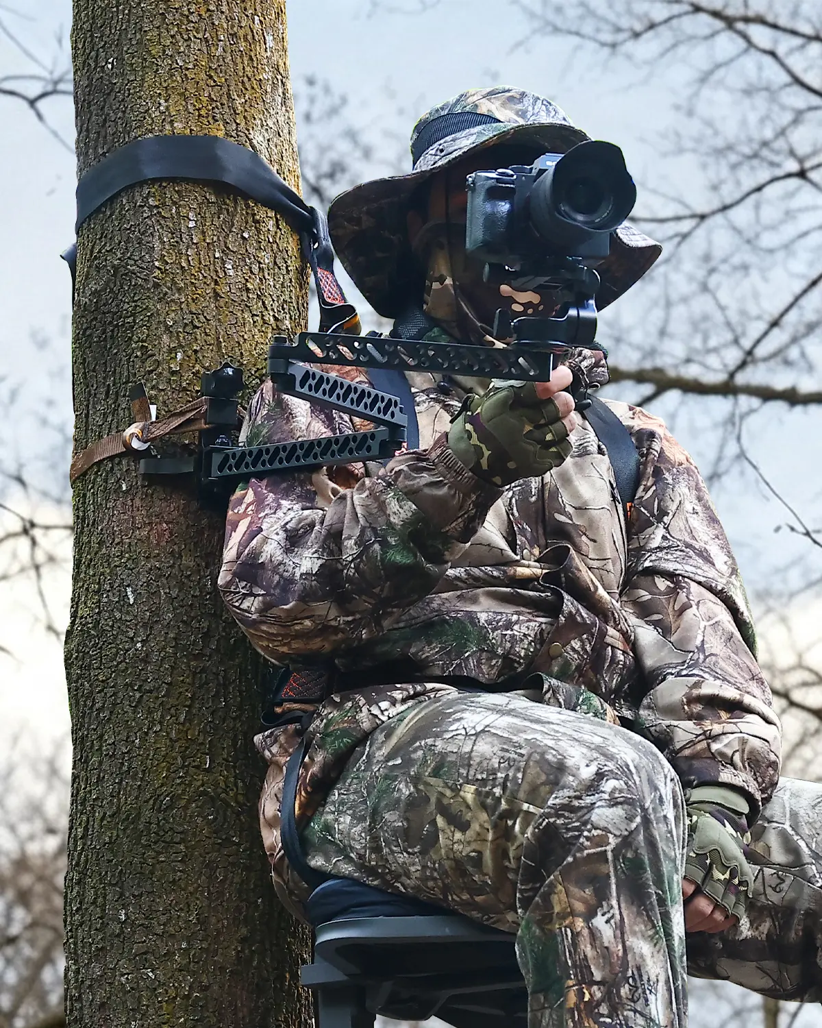 Hunter using a tree-mounted camera arm while sitting in a tree stand